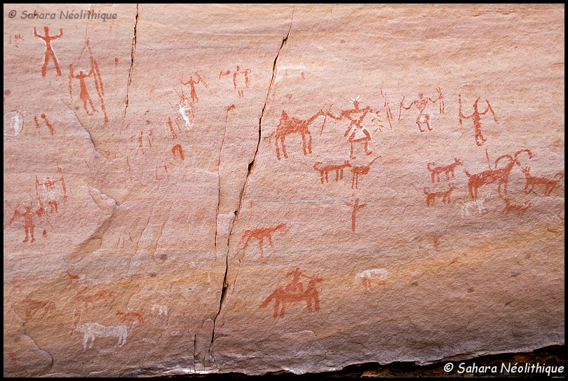 alidemma-30.jpg - École caméline "tassilienne" Les peintures se caractérisent par : des patines fraîches, souvent l' ocre est plus rouge que dans les périodes précédentes; un style très peu naturaliste et une forte tendance pour le schématisme. Les détails sont rendus de manière très sommaire, les proportions approximatives. présence d' un élément thématique. Ce peut être la présence d' un chameau ou bien d' inscriptions libyques et de tifinagh. Ce peut être aussi les représentations de personnages armés d' épées ou encore d' enclos à formes géométriques. 