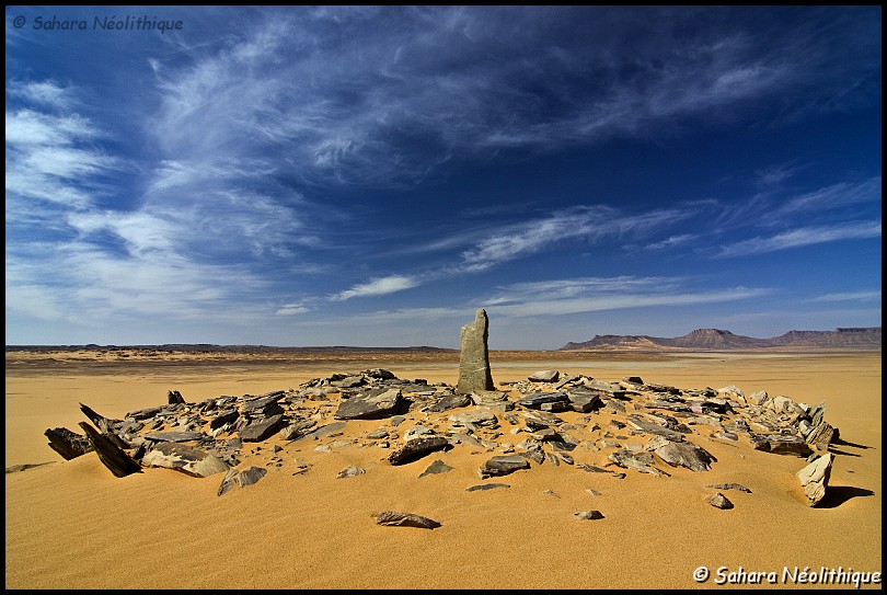 alidemma-35.jpg - Monument en pierres sèches dans le sillon intra-tassilien. Les hommes du néolithique n' étaient pas des primitifs comme beaucoup imaginent les hommes préhistoriques. Ils avaient la foi et la croyance qui transcendent la vie quotidienne. Les défunts n' étaient pas abandonnés mais soigneusement déposés en terre. Des fouilles sur le site de Tin Hanakaten, au sud-est de Djanet, ont révélé des squelettes placés dans un caisson de pierre recouvert d' un amas de blocs datés de 8000 BP.Mais ce qui attire le plus l' attention, ce sont les centaines de sépultures et autres monuments énigmatiques, parfois regroupés en nécropoles, que l' on peut voir dans tous les recoins du Sahara et que les Touaregs désignent sous le nom de idebnan.