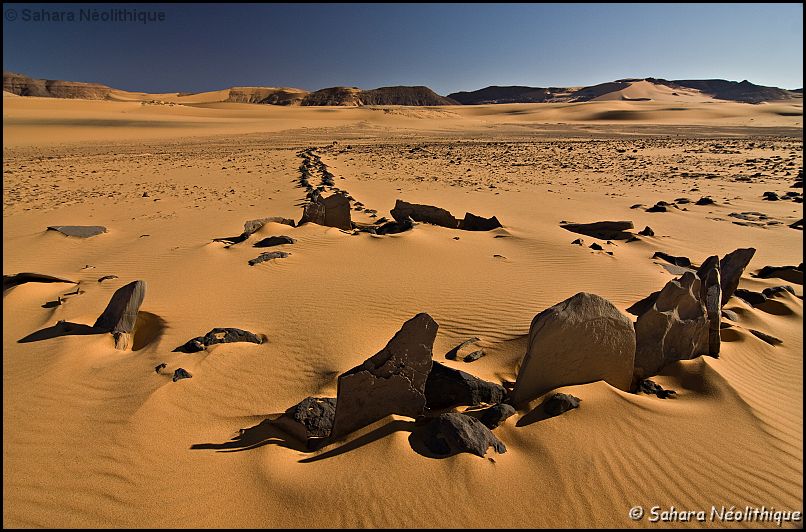 40d-IMG_4308a.jpg - De nombreux monuments en pierre sèches attestent de l'occupation de la Tadrart. Ici un monument "à antennes en V". On regroupe sous ce terme des structures que l' on peut décrire comme des plate-formes circulaires bordées par deux bras à cotés parallèles formant une sorte de "V".